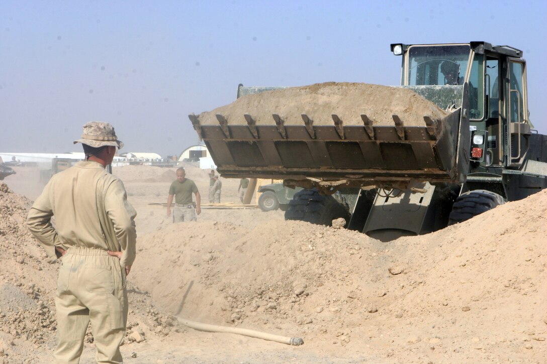 CAMP FALLUJAH, Iraq – Sergeant Clayton K. Anderson, a Phoenix native with Bulk Fuel, A Company, 6th Engineer Support Battalion, augmenting 8th ESB in direct support of Combat Logistics Bn. 8, 2nd Force Service Support Group (Forward), watches as a CLB-8 front-end loader adds dirt to the berm of a partially-completed fuel pit here July 26. The new pits are part of an expansion and renovation project for Camp Fallujah’s fuel farm. (Photo by Cpl. John E. Lawson Jr.)