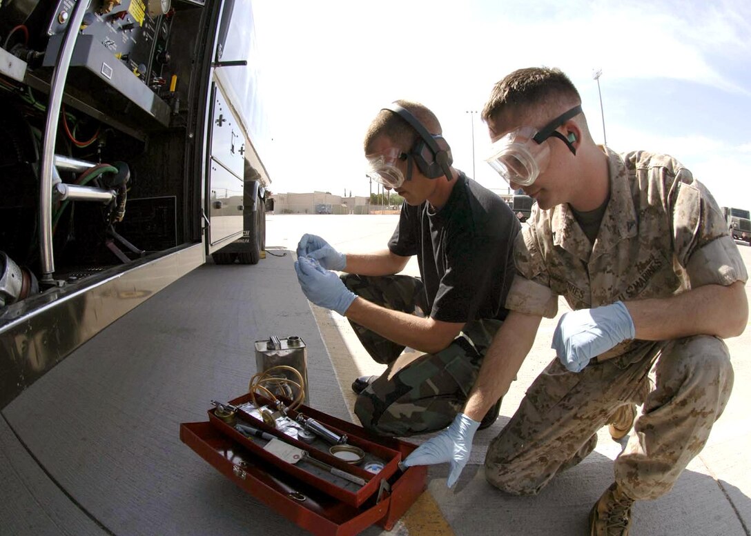 DAVIS-MONTHAN AIR FORCE BASE, Ariz. -- Senior Airman Brian Macmillan (left) and Marine Lance Cpl. Chris Squires perform quality testing on a refueling unit.  Airman Macmillan is a fuels analysis laboratory technician with the 355th Logistics Readiness Squadron, and Corporal Squires is a reservist performing two weeks of training here.  (U.S. Air Force photo by Airman 1st Class Christina D. Ponte)