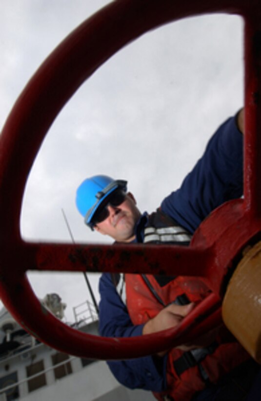 Coast Guard Petty Officer 2nd Class Chris Williams cranks the brake on the anchor chain of the Coast Guard Cutter Bear as the cutter anchors off Sao Tome and Principe in Africa, on July 19, 2005. 