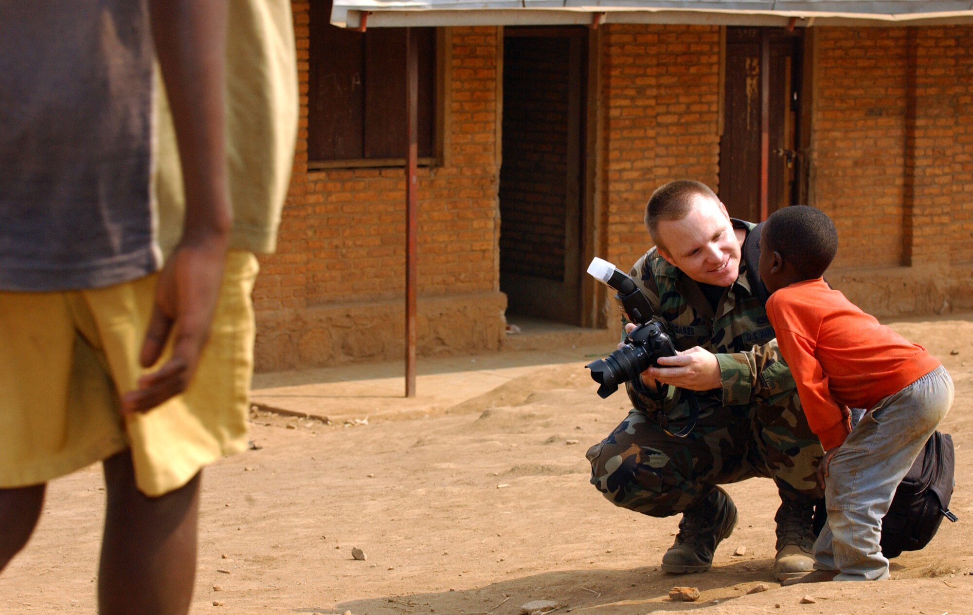 KIGALI, Rwanda -- Senior Airman Mike Meares, of the 86th Air Expeditionary Group public affairs office, shows a local child his photo on the back of his digital camera July 28. The group donated soccer balls, soccer nets, candy and toys to the children attending the Nonko Primary School  of Kigali-Kanombe, Rwanda.  The United States provided transportation for 1,200 Rwandan forces to and back from Sudan in support of AMIS 2, the African Union Mission in Sudan. (U.S. Air Force photo by SSgt Bradley C. Church).