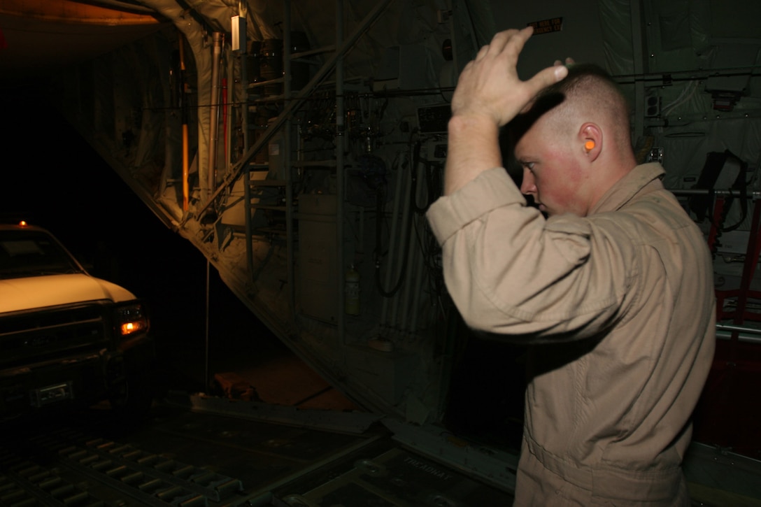 AL ASAD, Iraq - Corporal Eric Hilker, a loadmaster with Marine Aerial Refueler Transport Squadron 252 and Ithaca, N.Y., native, directs a vehicle onto the KC-130J here July 28. The KC-130J is used to transport cargo and passengers throughout Iraq, along with mid-air refueling.