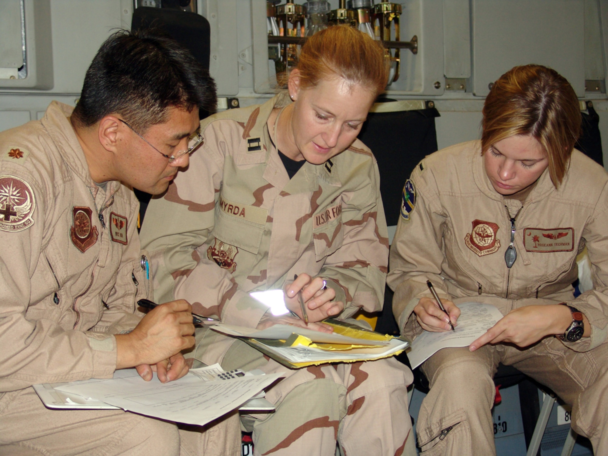 SOUTHWEST ASIA -- (From left) Maj. Vince Oda, Capt. Stephanie Myrda, and 1st Lt. Roseann Teckman review and annotate medical records inside a C-17 Globemaster III cargo compartment at a forward-deployed location.  They are assigned to the 386th Contingency Aeromedical Staging Facility.  (U.S. Air Force photo by Staff Sgt. Carlos Diaz)