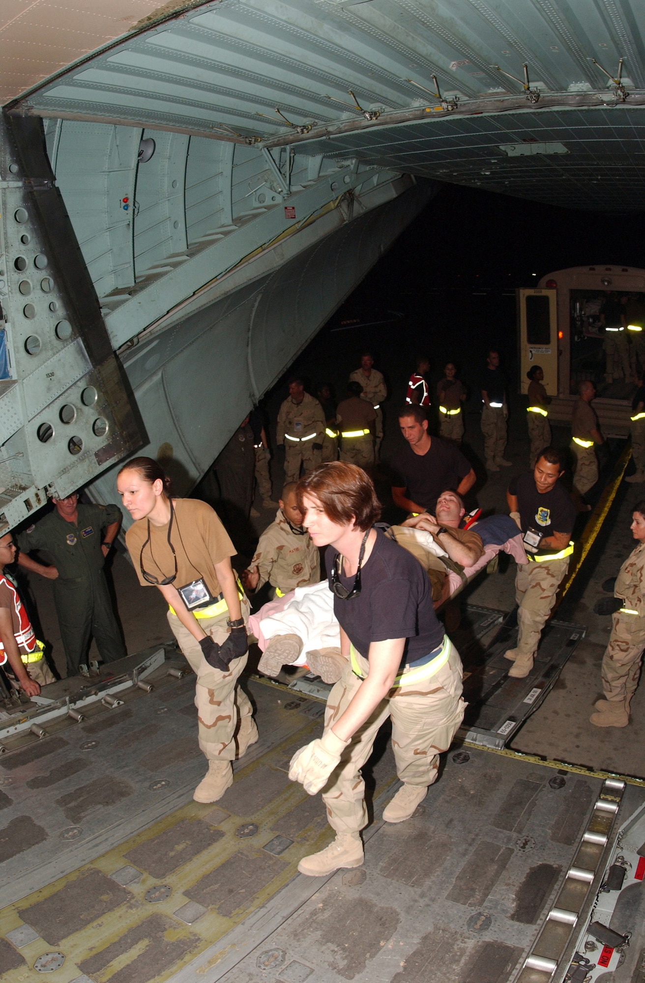 BALAD AIR BASE, Iraq -- (From left) Airman 1st Class Debra Camacho, Staff Sgt. Fred Mathis, Tech. Sgt. Marsha Madsen, Senior Airman Bradley Cross and Staff Sgt. Raymond Wrentmore carry Navy Petty Officer 3rd Class Lorphy Bourque aboard a C-130 Hercules to fly him to Ramstein Air Base, Germany.  The Airmen are assigned to the 332nd Air Expeditionary Wing here. (U.S Air Force photo Senior Airman Tim Beckham)