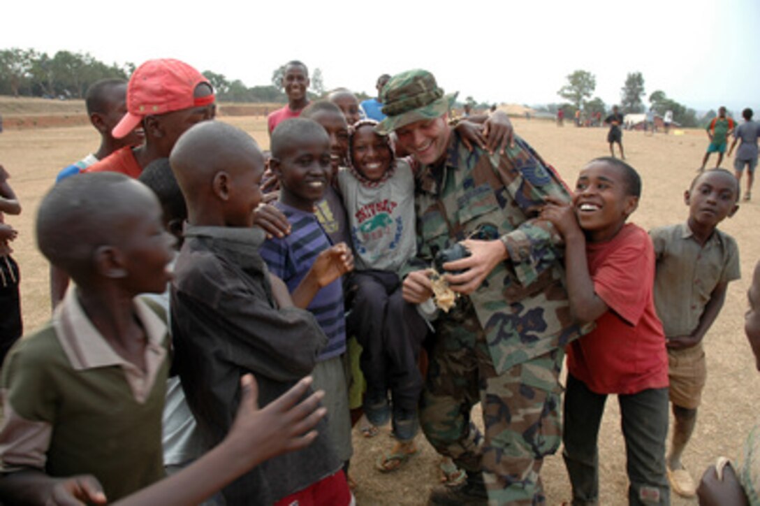 Rwandan boys surround Air Force Tech. Sgt. Todd Jackson as he tries to wrap a homemade ball made of plastic bags with green ordnance tape on at the Nonko Primary School in Kigali-Kanombe, Rwanda, on July 27, 2005. The airmen of the 86th Air Expeditionary Group pitched in to donate soccer balls, soccer nets, candy and toys to the children attending the school. Before the donations the school had one soccer ball and one volleyball. Jackson is a security forces airman deployed from Ramstein Air Base, Germany. 