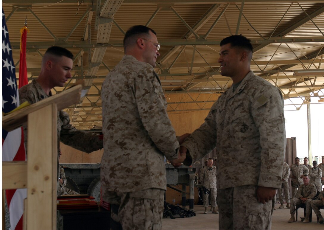 AL ASAD, Iraq -- Corporal John R. Pain, a Pacifica, Calif., native, shakes hands with Col. William S. Aitken, Combat Logistics Battalion 2 commanding officer during Corporals’ Course graduation here July 31, 2005.  Pain, an air deliver specialist with Transportation Support Company, CLB-2, rose above 25 of his peers to earn the title distinguished honor graduate of Corporals’ Course class 07-05.