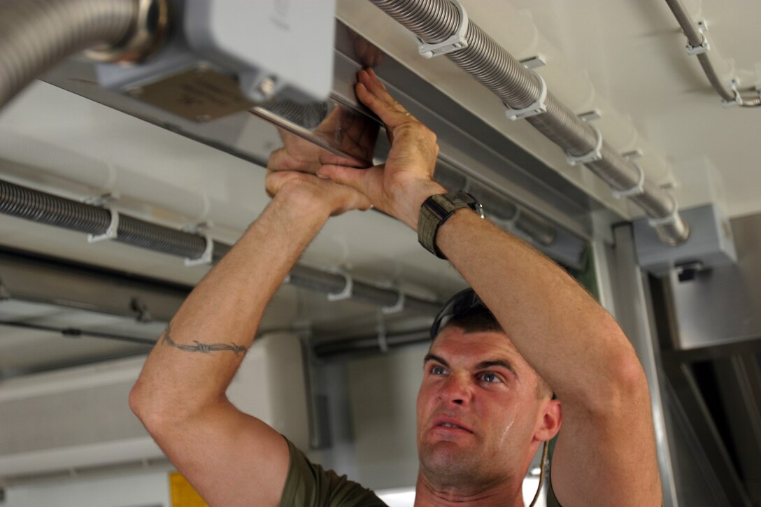 CAMP HIT, Iraq - Sergeant Daniel Johnson, a food service specialist with Headquarters and Service Battalion, 2d Force Service Support Group (Forward), attempts to fit a panel used to seal two iso-containers of the Field Food Service System.  The Houston native helped set up the second FFSS in Iraq, and is responsible for the maintenance of the FFSS set up in Korean Village, Iraq.