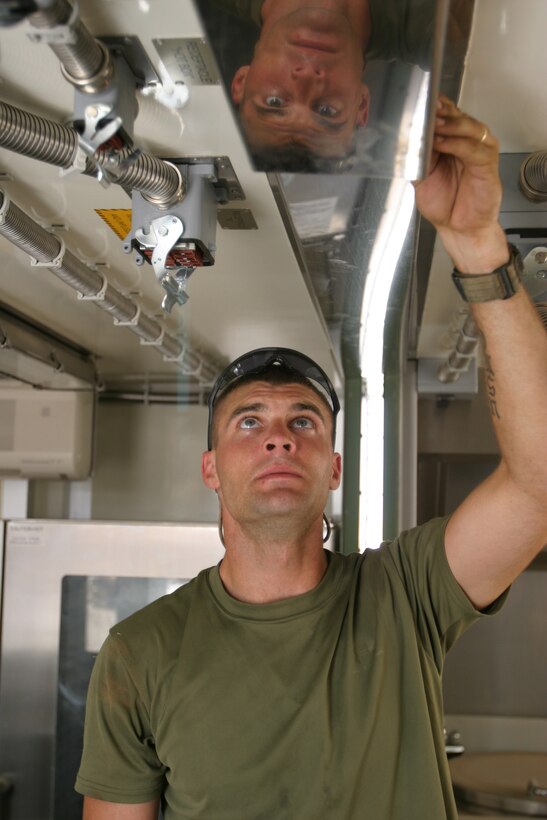 CAMP HIT, Iraq - Sergeant Daniel Johnson, a food service specialist with Headquarters and Service Battalion, 2d Force Service Support Group (Forward), checks the fit of a panel used to seal two iso-containers.  The Houston native and 12 other Marines set up the Marine Corps' third generation of Field Food Service Systems.  (Photo by Cpl. C.J. Yard)
