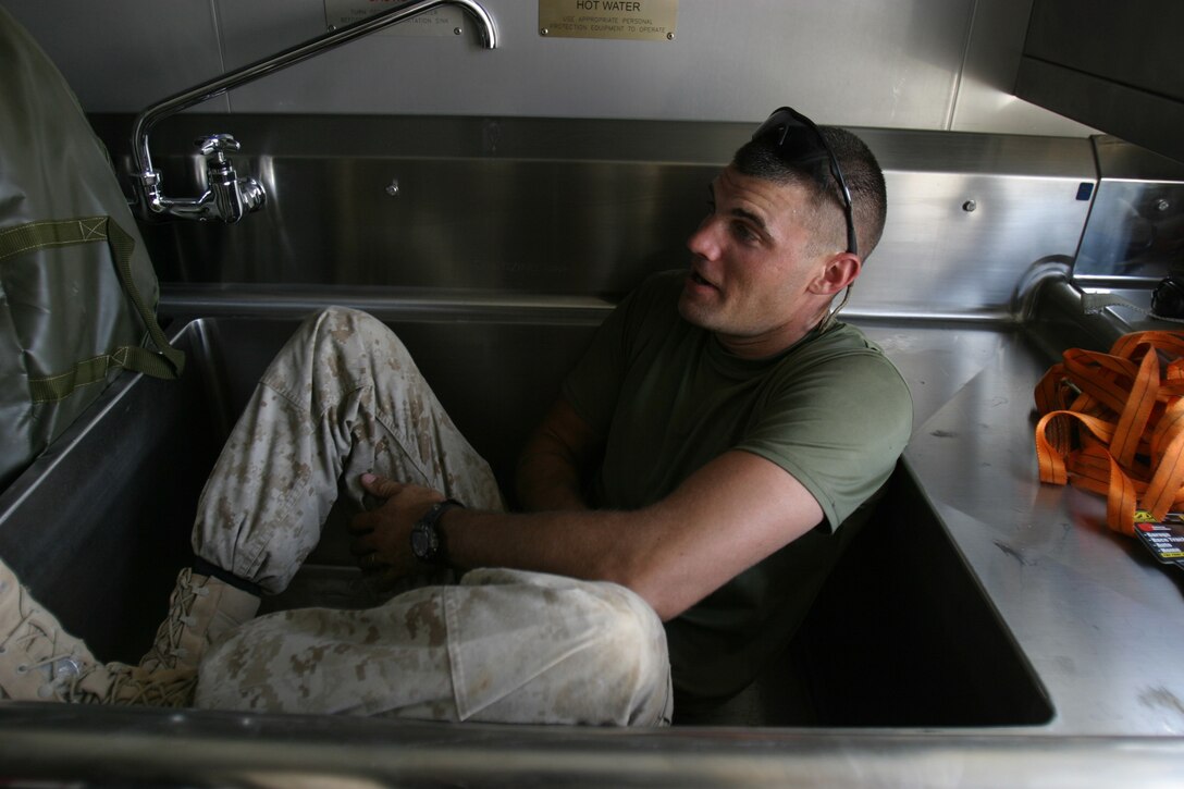 CAMP HIT, Iraq - Sergeant Daniel Johnson, a food service specialist with Headquarters and Service Battalion, 2d Force Service Support Group (Forward), takes a break from the heat and setting up the Marine Corps' third generation Field Food Service System.  The Houston native is responsible for the maintenance of the other FFSS in Iraq at Korean Village.