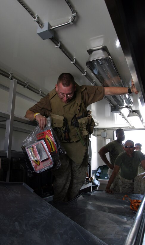 CAMP HIT, Iraq - Gunnery Sgt. Aaron L. Barthelmas, a mess chief with Headquarters and Service Battalion, 2d Force Service Support Group (Forward), pulls tools out of containers packed in a Field Sanitation Unit.  The FSU is part of the Marine Corps' third generation Field Food Service System.  Barthelmas, a Circleville, Ohio, native, helped set up the FFSS here, the second one he's helped set up in Iraq. (Photo by Cpl. C.J. Yard)