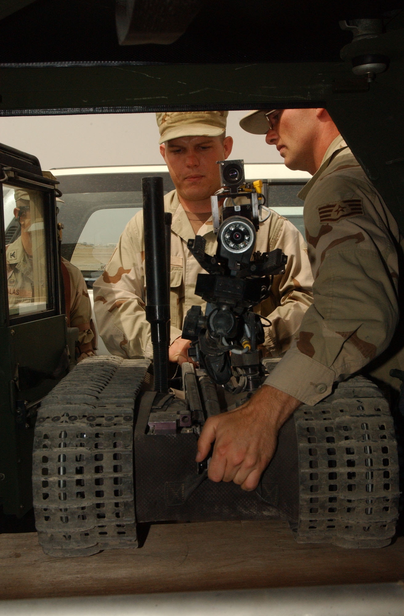 BALAD AIR BASE, Iraq -- Staff Sgts. Clay Sigler (left) and Robert Butler unload a robot from the back of a Humvee here.  Two small robots can be loaded into the vehicle and taken on a call.  The Airmen are 332nd Explosive Ordnance Disposal technicians.  (U.S. Air Force photo by Senior Airman Shaun Emery)