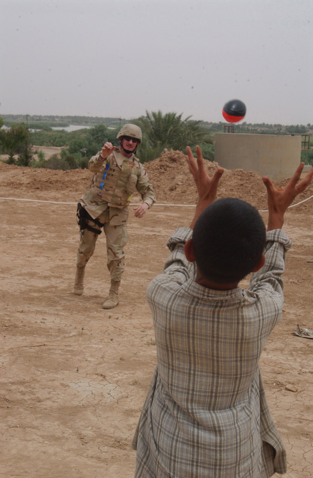 IRAQ -- Staff Sgt. John Shepard plays catch with a boy during a recent humanitarian visit to a local village.  He is a chaplain's assistant with the 332nd Air Expeditionary Wing at Balad Air Base.  (U.S. Air Force photo by Senior Airman Shaun Emery)               