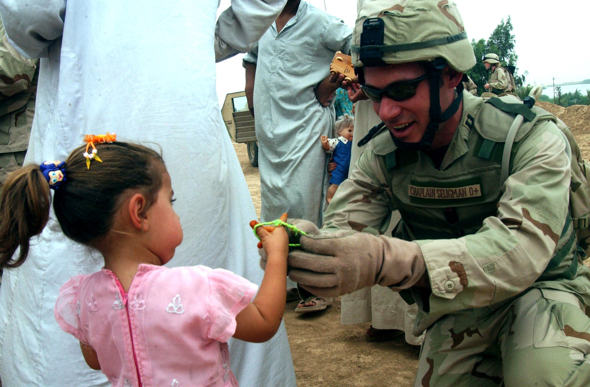 IRAQ -- Chaplain (Capt.) Charles Seligman gives a local girl a bracelet during a humanitarian visit.  The chaplain, along with volunteers from Balad Air Base, spent time at a local village handing out gifts as part of their mission to maintain and improve relations with Iraqis.  He is assigned to the 332nd Air Expeditionary Wing.  (U.S. Air Force photo by Senior Airman Shaun Emery)                  