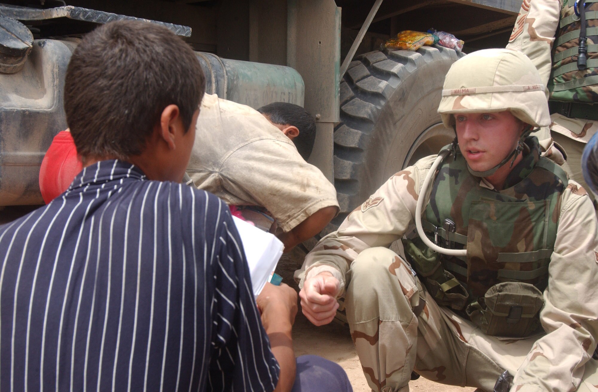 IRAQ -- Airman 1st Class Cory Halma gives supplies to a local boy during a humanitarian trip.  Airman Halma volunteered to travel off the base to help improve relations between Balad Air Base Airmen and their Iraqi neighbors.  He is assigned to the 332nd Expeditionary Communications Squadron.  (U.S. Air Force photo by Senior Airman Shaun Emery)    