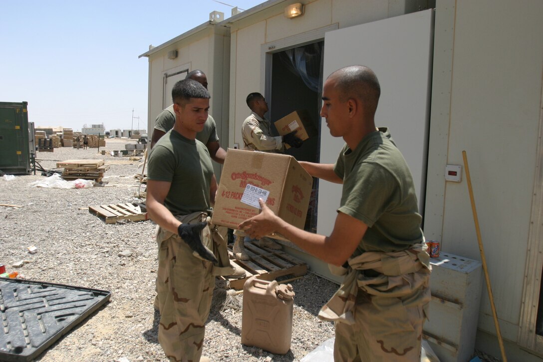 CAMP HIT, Iraq - Food service specialists with Headquarters and Service Battalion, 2d Force Service Support Group (Forward), pass boxes into a refrigeration unit to keep perishable food items out of the sun.  (Photo by Cpl. C.J. Yard)