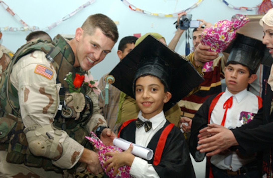 U.S. Army Capt. Sam Donnelly hands out diplomas and gifts to students in their makeshift caps and gowns at a grade school graduation ceremony in Tikrit, Iraq, on May 26, 2005. Donnelly and his fellow soldiers from the 2nd Division, 7th Infantry Battalion of Fort Stewart, Ga., and civil affairs representatives from Forward Operating Base Danger assisted the school's ceremony. 