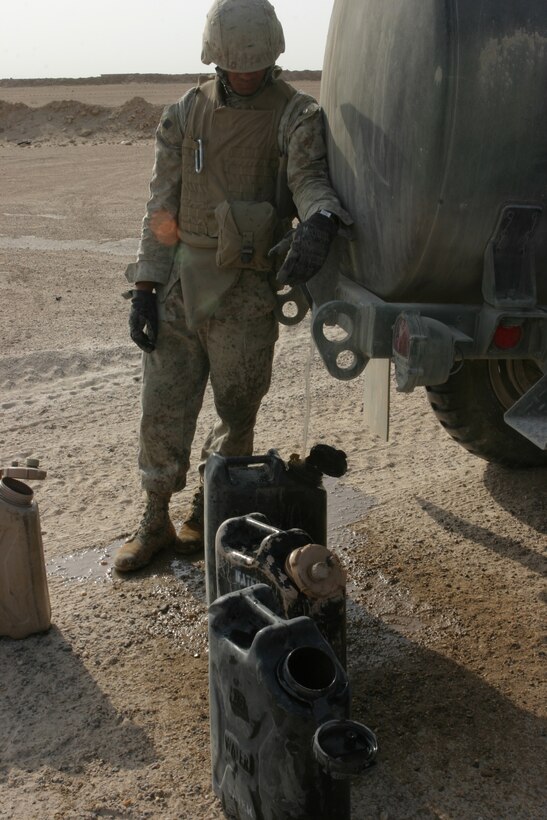 CAMP TAQADDUM, Iraq (June 4, 2005) - Lance Cpl. Adam Brewster, a 20-year-old Rapid City, S.D., native, and heavy equipment operator with Support Company, 8th Engineer Support Battalion, 2d Force Service Support Group (Forward), fills water jugs so he can mix concrete used to repair holes caused by Improvised Explosive Devises and heavy travel. The Marines of 8th ESB conducted Operation San Juan, a five-day operation repairing Alternate Supply Route San Juan, making it safer for convoys and local civilians traveling the road on a daily basis.