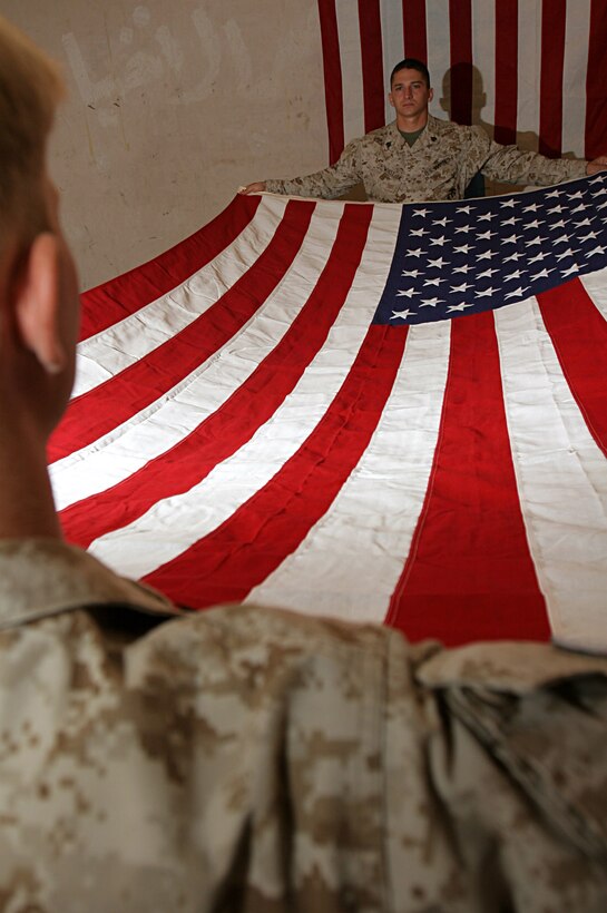 AL ASAD, Iraq (June 6, 2005) - Sgt. Daniel H. Whitt, (right) native of Snellville, Ga., and Cpl. Joshua P. Himes, native of Newnan, Ga., both mortuary affairs specialists spread an American flag to honor fallen coalition forces personnel and contractors. The Marines of Mortuary Affairs, Detachment Al Asad, Service Company, Headquarters and Service Battalion, 2nd Force Service Support Group are tasked with recovering, processing and evacuating deceased personnel to their families as expeditiously as possible.