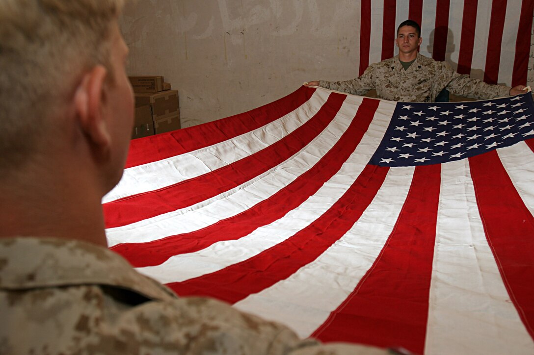AL ASAD, Iraq (June 6, 2005) - Sgt. Daniel H. Whitt, (right) native of Snellville, Ga., and Cpl. Joshua P. Himes, native of Newnan, Ga., both mortuary affairs specialists spread an American flag to honor fallen coalition forces personnel and contractors. The Marines of Mortuary Affairs, Detachment Al Asad, Service Company, Headquarters and Service Battalion, 2nd Force Service Support Group are tasked with recovering, processing and evacuating deceased personnel to their families as expeditiously as possible.