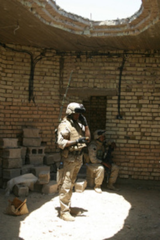 Marine Lance Cpl. Jamie Davidson is bathed in light from a hole in the roof as he radios in his current position during a security halt in Kharma, Iraq, on May 29, 2005. Davidson's unit, Lima Company, 3rd Battalion, 8th Marine Regiment, is conducting counter-insurgency operations with Iraqi Security Forces to isolate and neutralize anti-Iraqi Forces in the area. Davidson is assigned to the 2nd Squad, 4th Platoon of Lima Company. 