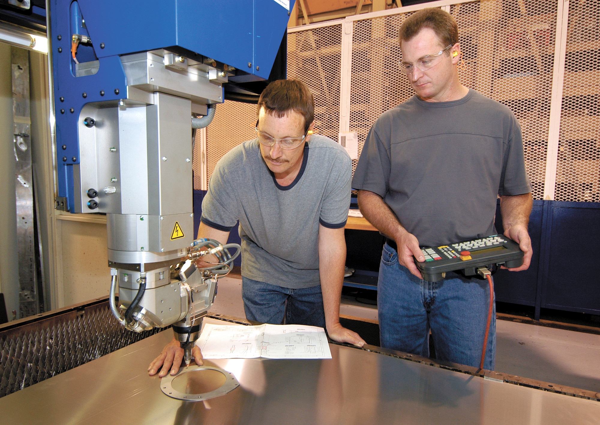 TINKER AIR FORCE BASE, Okla. -- Ricky Harris (left) and Paul Spurlock can program the carbon dioxide laser to precisely carve small or large engine parts quieter, cleaner and safer than many other methods.  They are machinists with the computer numerical control shop here.  (U.S. Air Force photo by Margo Wright)