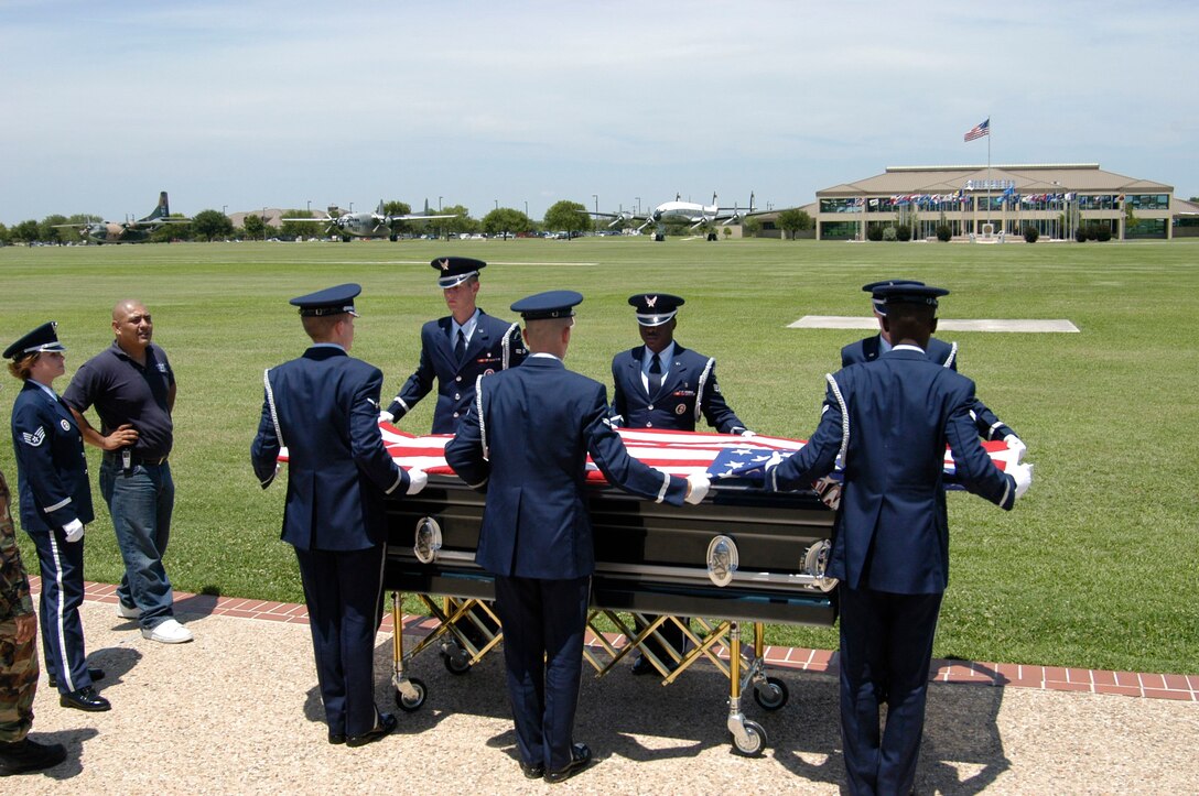 LACKLAND AIR FORCE BASE, Texas -- Honor guard pallbearers stretch the flag out flat before folding it during the filming of a performance on the parade grounds here.  Airmen of the 37th Communications Squadron are producing a three-to-five minute honor guard mission video to help recruit new honor guard members.  (U.S. Air Force photo by James Coburn)