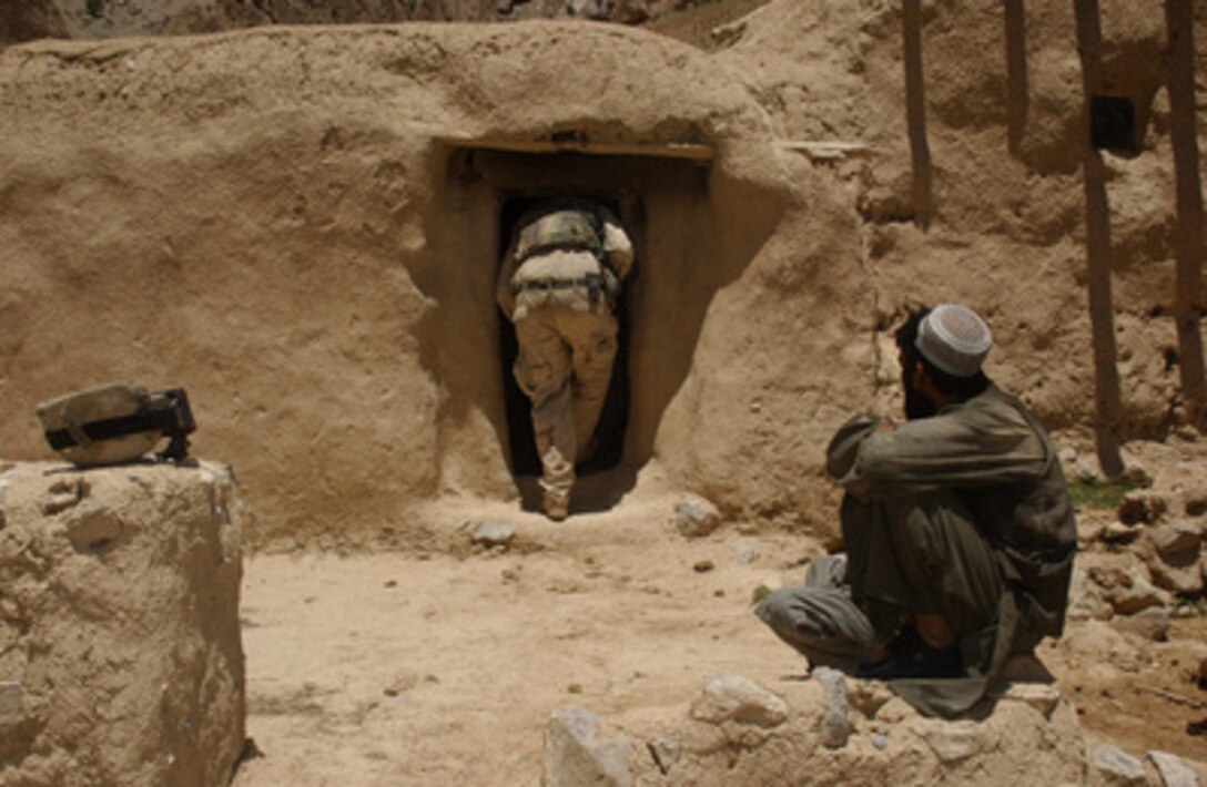 A soldier from the 29th Infantry Division of the Virginia National Guard stoops to enter and search the home of a suspected Taliban member in Afghanistan on June 4, 2005. 