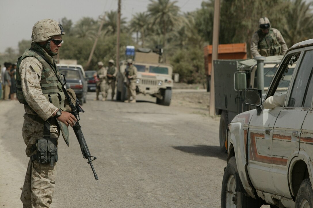 Corporal Robert "Bobby" W. Higdon, 22, Team 2, Detachment 2, 5th Civil Affairs Group, II Marine Expeditionary Force (FWD)and Glen Burnie, Md. native, controls the traffic flow during a visit to the city of Karmah, Iraq June 9, 2005.