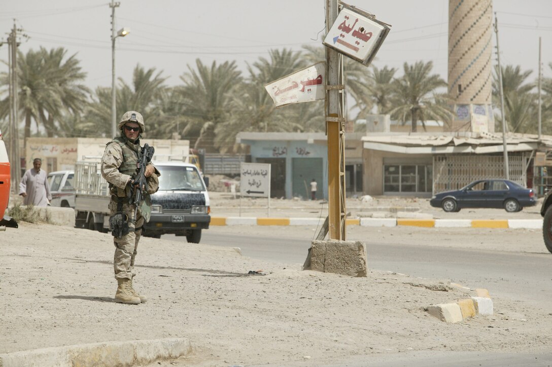 Corporal Robert "Bobby" W. Higdon, 22, Team 2, Detachment 2, 5th Civil Affairs Group, II Marine Expeditionary Force (FWD)and Glen Burnie, Md. native, provides security and controls traffic flow during a visit to the city of Karmah, Iraq June 9, 2005.