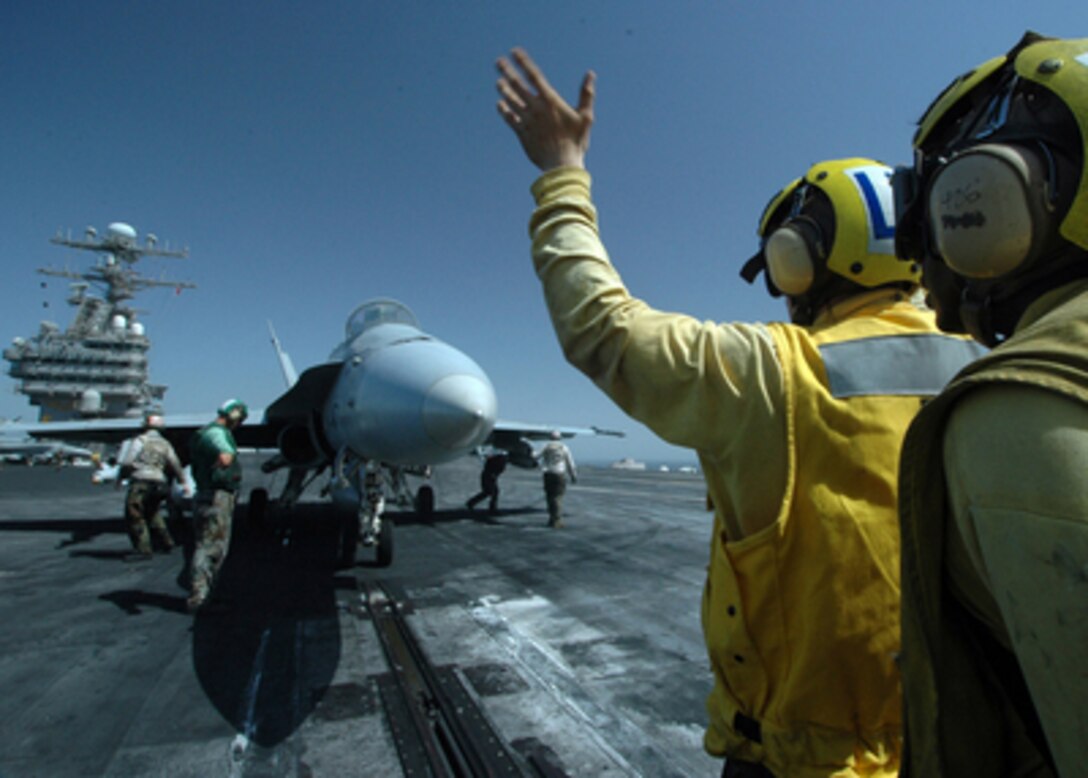 Aviation Boatswain's Mate 3rd Class Kaylon Boston (right) keeps a close eye over Airman Jonathan Temper's shoulder while performing training on directing an F/A-18C Hornet onto one of four steam powered catapults during flight operations aboard the aircraft carrier USS Carl Vinson (CVN 70) on June 8, 2005. The Carl Vinson Carrier Strike Group is conducting operations in support of multi-national forces in Iraq and maritime security while underway in the Persian Gulf. 