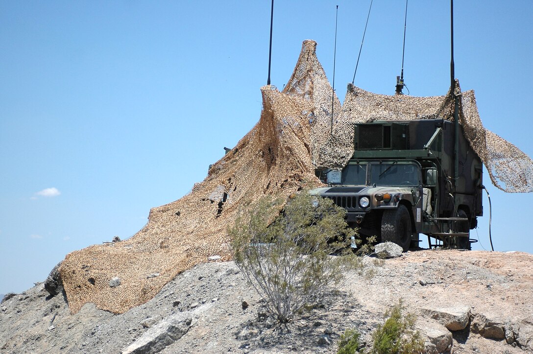 A Hum-V providing Communication for MASS-1 sit atop a lonely hill half covered in Desert pattern Cami Netting
