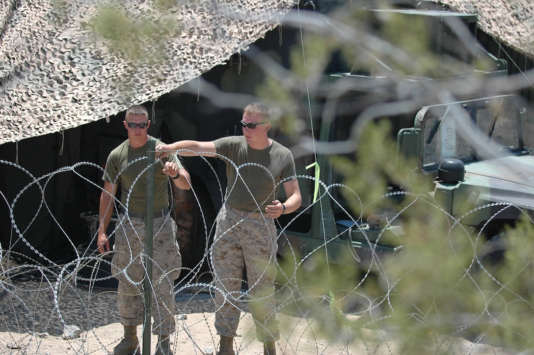 Lance Cpl. Philip Rummells, an airconditioning technician with MASS-1 and Lance Cpl. Austin Wagner, a generator mechanic who is going with Rummells to Iraq in July, sets up barbed wire around the tent where the Marines of MASS-1 at perfecting their job skills in a realistic environment at Exercise Desert Talon.
