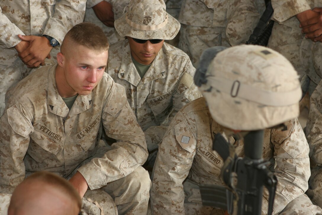 AL ASAD, Iraq (June 14, 2005) - Lance Cpl. Aliaksandr Petushok, along with fellow Marines from 4th Squad, Military Police Detachment, and friends gather around to pay their last respects to Lance Cpl. Marc L. Tucker, a motor transportation operator augmented as a military policeman, MP Detachment, Combat Logistics Battalion 2, 2d Force Service Support Group (Forward).  Tucker, a Pontotoc, Miss., native, was attached to 4th Squad, MP Detachment, and deployed to Iraq to provide security for the explosive ordnance disposal team, recovery missions, engineer crater repair missions and convoys. He lost his life while supporting Operation Iraqi Freedom 04-06. During the memorial service, Tucker's friends talked about how he influenced and touched each one of their lives. They talked about the funny memories and what they are going to miss.  Most of the Marines spoke of the great amount of respect and love they have for their "brother."