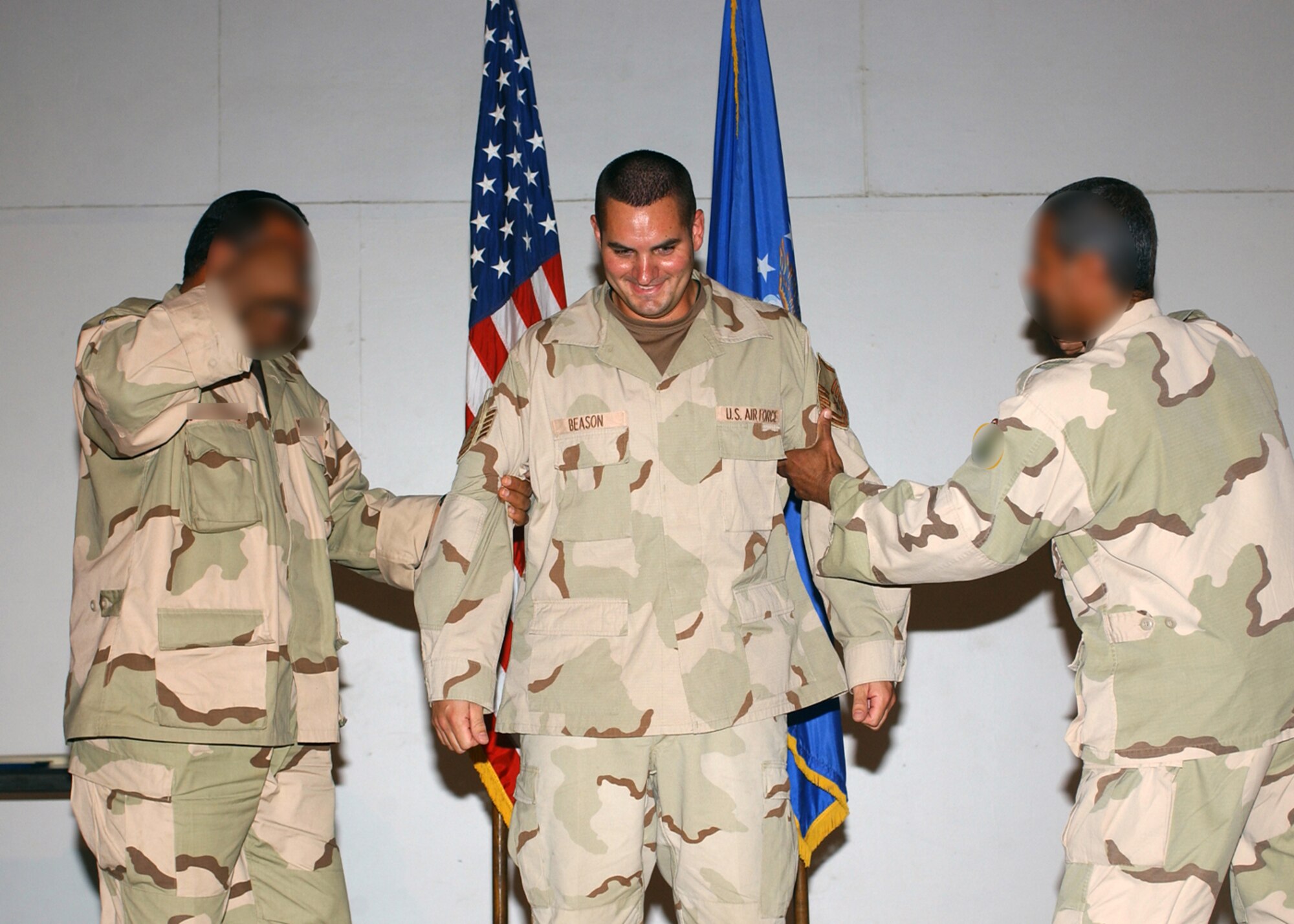 TALLIL AIR BASE, Iraq -- Two Iraqi airmen tack new stripes on Master Sgt. Bubba Beason during his promotion ceremony here.  Sergeant Beason is the airmen's hydraulics instructor.  He said he wanted the students to tack on his stripes because they and the rest of their countrymen are part of the reason he got promoted in the first place.  Sergeant Beason is assigned to the 777th Expeditionary Aircraft Maintenance Squadron.  The students' faces are blurred for their protection.  (Altered U.S. Air Force photo by Master Sgt. Maurice Hessel)