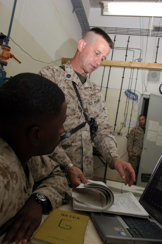 AL ASAD, Iraq ? Gunnery Sgt. Steven Teague administration chief with Marine Fighter Attack Squadron 142 discusses a travel claim issue with his administration clerk, Cpl. Marques Bates. Teague is a general residential contractor and owns his own business in Covington, Ga.