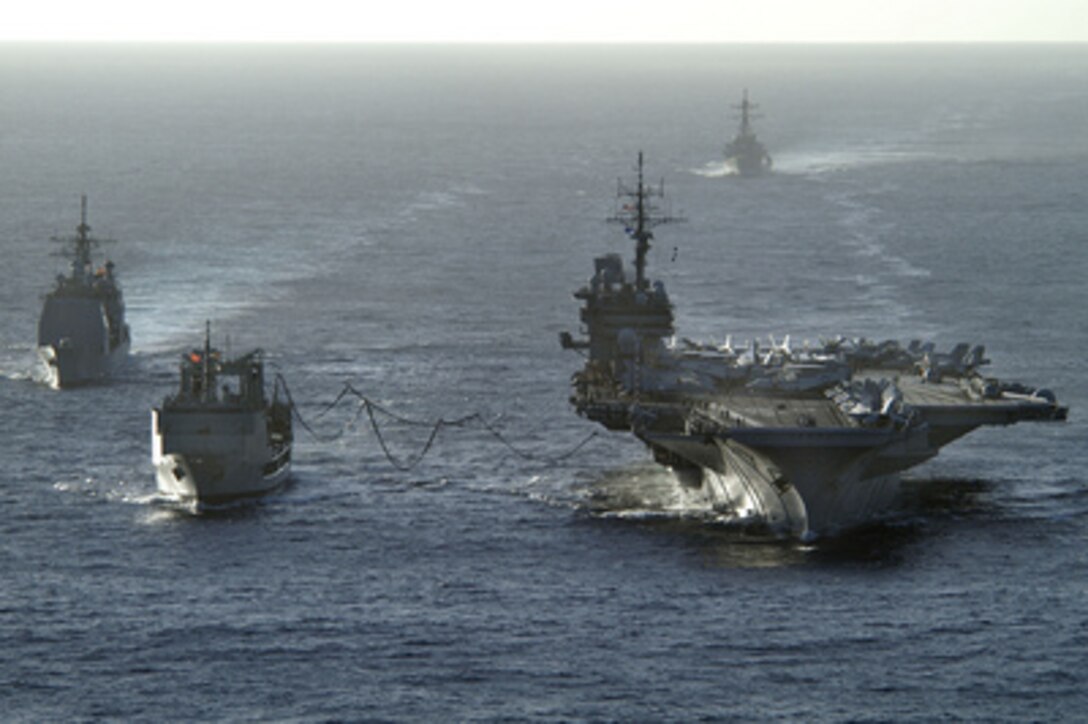 The aircraft carrier USS Kitty Hawk (CV 63) receives fuel during a replenishment at sea from the Royal Australian Navy auxiliary oiler replenishment vessel HMAS Success (AOR 304) as U.S. Navy guided missile cruiser USS Cowpens (CG 63) steams alongside and guided missile destroyer USS John Paul Jones (DDG 53) trails behind, on June 14, 2005. The ships are operating in the Coral Sea, off the coast of Australia's Queensland region, as part of Exercise Talisman Saber 2005. Talisman Saber is a combined U.S.-Australia command post and field training exercise, demonstrating the U.S. and Australian commitment to the military alliance and regional security. 