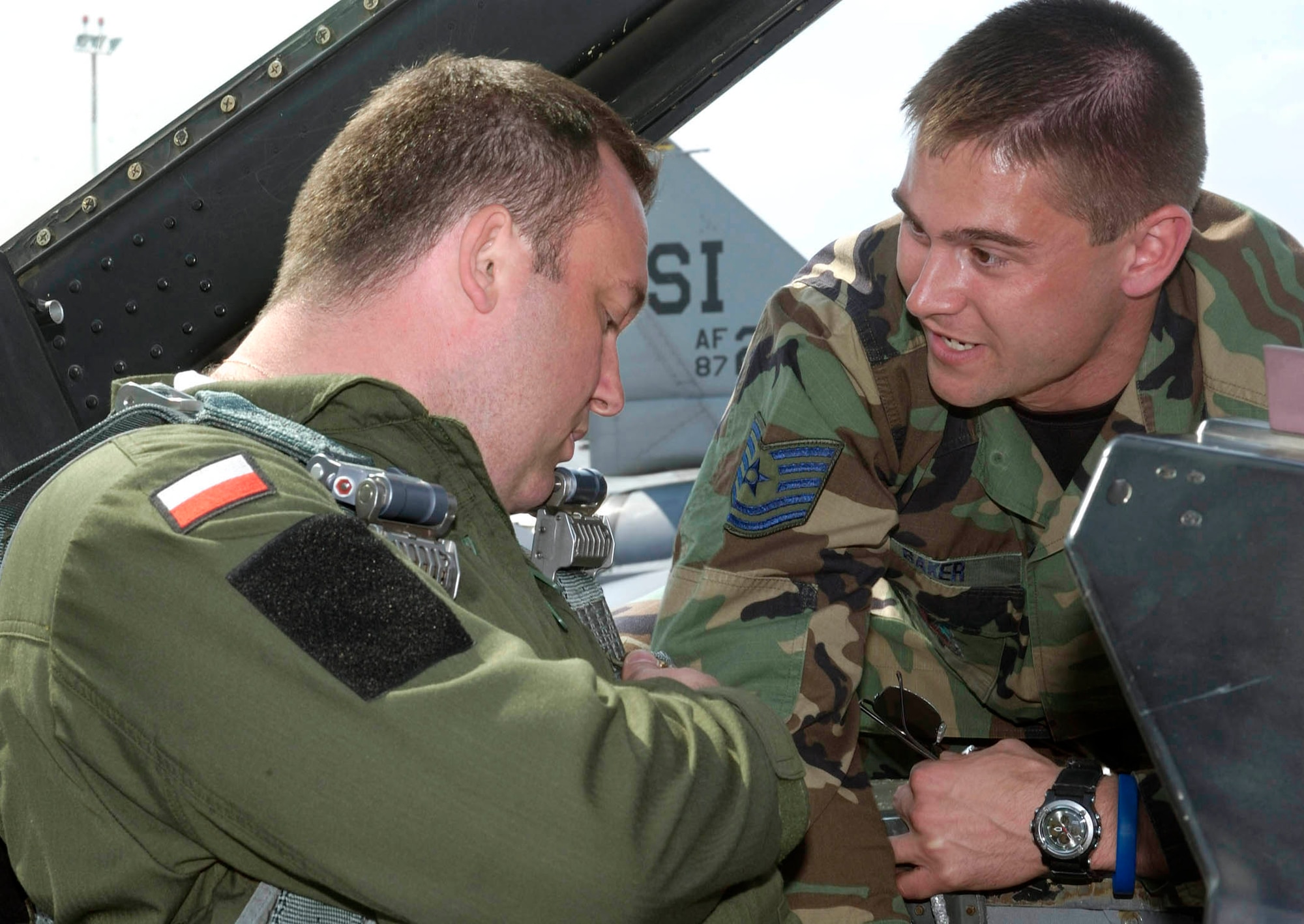 POZNAN, Poland -- Tech. Sgt. Brenton Baker reviews F-16 Fighting Falcon seat procedures with Polish air force Capt. Arkadiesz Kurkiewicz here.  Airmen from the Illinois Air National Guard's 183rd Fighter Wing are familiarizing Polish airmen with the F-16 during the U.S. European Command exercise Sentry White Falcon 2005 through June 17.  In 2006, the Polish air force will start receiving their own F-16s that will begin replacing their Soviet-made MiG fighters as the country modernizes its military to NATO standards.  Sergeant Baker is a life support technician with the wing.  (U.S. Air Force photo by Master Sgt. John E. Lasky)