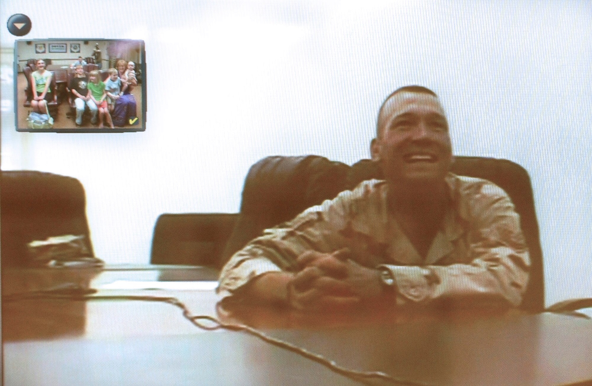 DOVER AIR FORCE BASE, Del. -- Pictured on a television screen, Tech. Sgt. Bill Vass speaks with his wife and five children (upper left) via video teleconference June 15 from Balad Air Base, Iraq.  Sergeant Vass and five other deployed Airmen from here were given 15-minute live video visits from their families as an early Father's Day surprise.  (U.S. Air Force photo by Doug Curran)