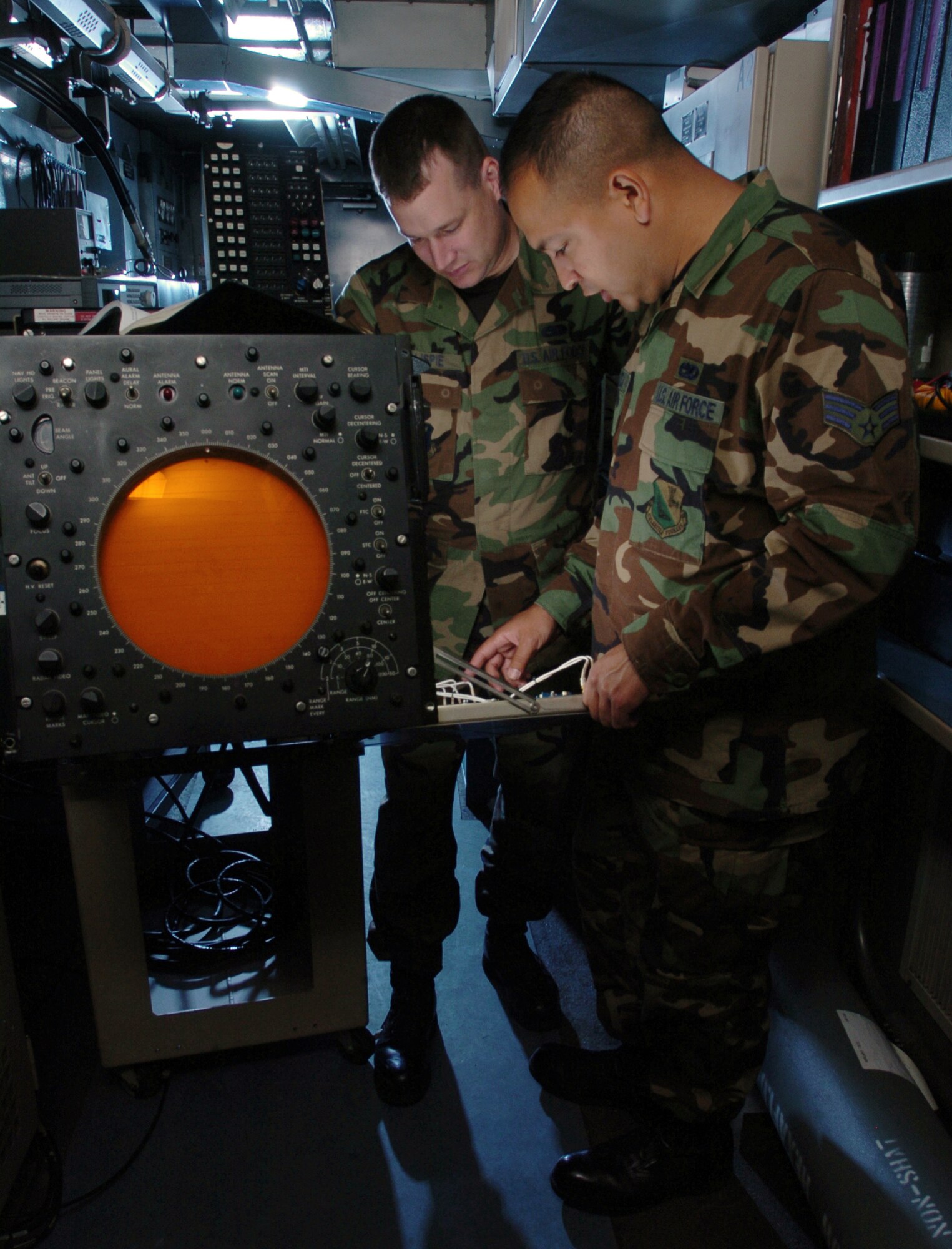 YOKOTA AIR BASE, Japan -- Senior Airman Raul Sauceda (foreground) and Staff Sgt. Chris Gillispie inspect a radar scope at their facility here.  The scope is used by air traffic controllers as a visual aid to guide incoming and outgoing aircraft.  The Airmen are ground radar technicians with the 374th Communications Squadron.  (U.S. Air Force photo by Master Sgt. Val Gempis)