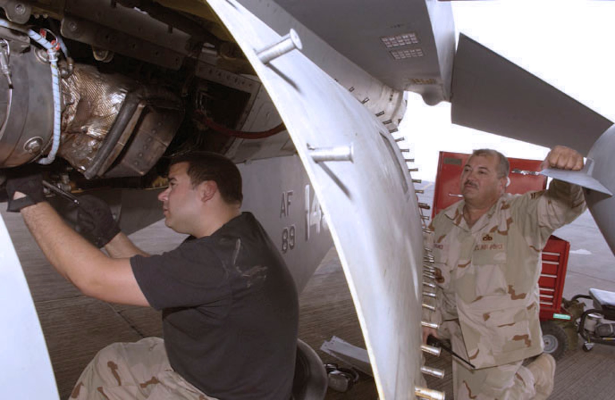 SOUTHWEST ASIA -- Staff Sgt. Joe Franco (left) repairs an F-16 Fighting Falcon while his father, Senior Master Sgt. Joe Franco, supervises.  The father and son are assigned to the 379th Expeditionary Aircraft Maintenance Squadron at a forward-deployed location and are from the Oklahoma Air National Guard's 138th Fighter Wing.  (U.S. Air Force photo by Tech. Sgt. Randy Mallard)
