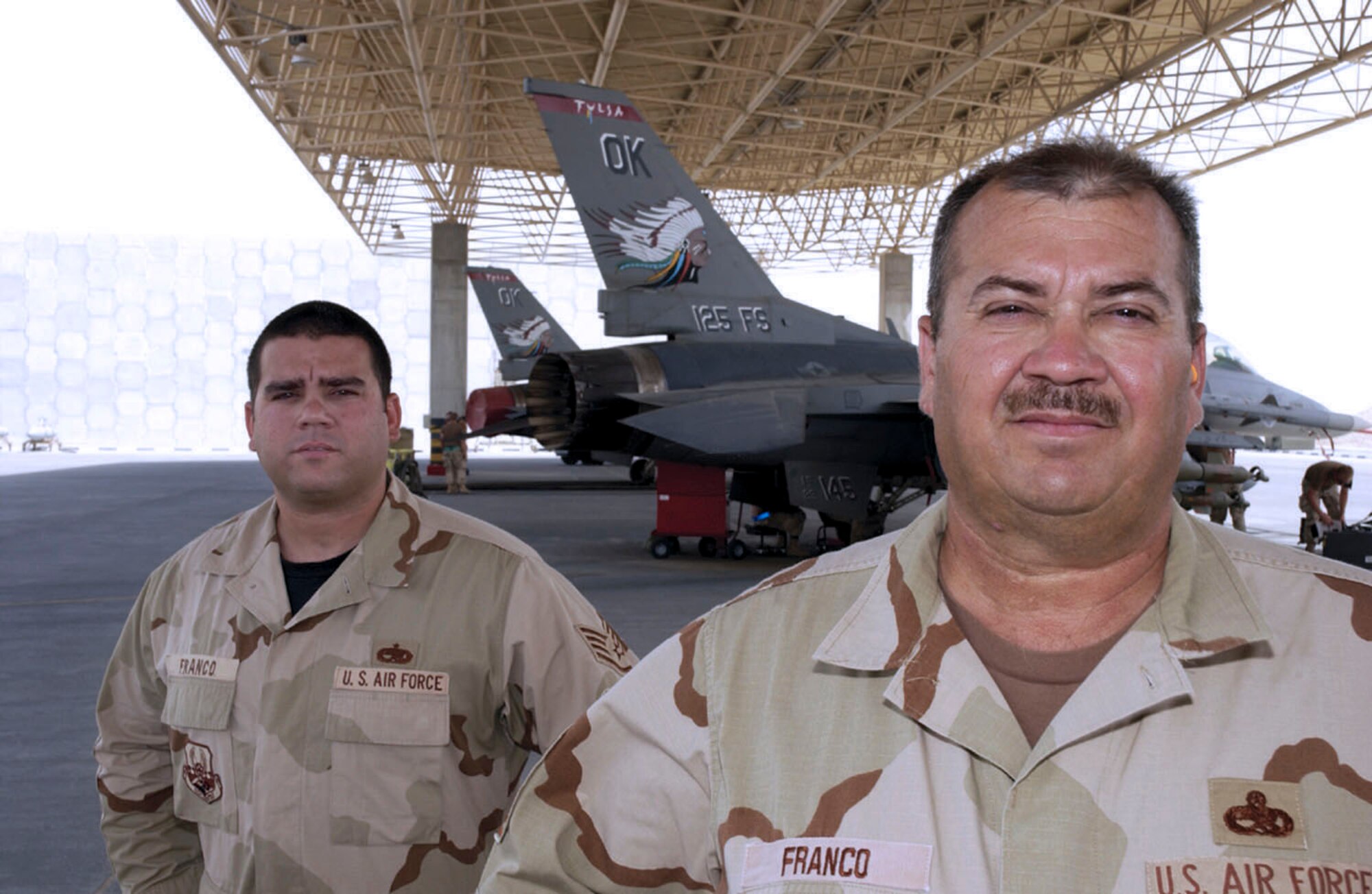 SOUTHWEST ASIA -- Senior Master Sgt. Joe Franco (foreground) and Staff Sgt. Joe Franco take a moment in between maintenance jobs.  The father and son are assigned to the 379th Expeditionary Aircraft Maintenance Squadron at a forward-deployed location and are from the Oklahoma Air National Guard's 138th Fighter Wing.  (U.S. Air Force photo by Tech. Sgt. Randy Mallard)