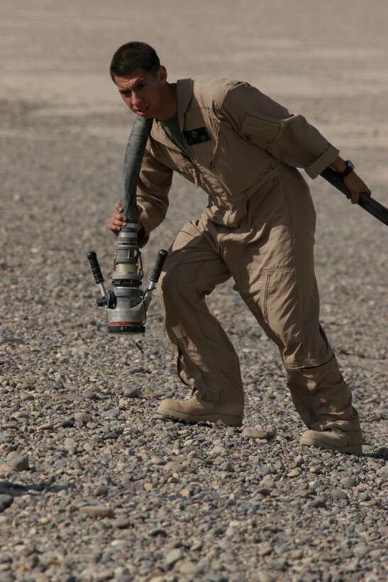 CAMP FALLUJAH, Iraq - Lance Cpl. Edwin Lazo, a bulk fuel specialist with Marine Wing Support Squadron 371 carries a hose as the fuels Marines construct their forward arming and refueling point. The construction of the refueling system takes 10 minutes and can fuel two aircraft at a time.