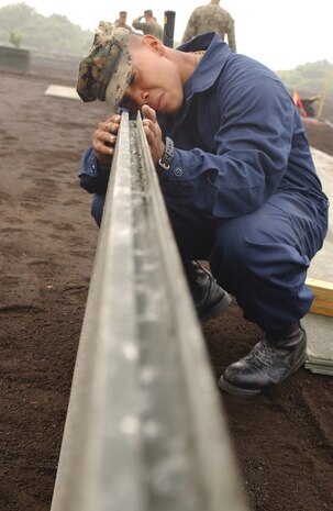 Pfc. Troy Norman, Marine Wing Support Squadron 171 expiditionary airfield services crewmember, looks down the track of a 12 foot length of Alluminum mating checking for obstructions before it is set into place in the Vertical Take Off and Landing pad, June 20.