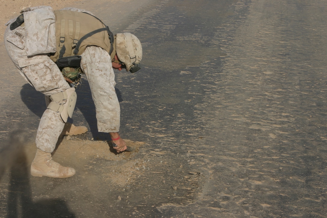 AL ASAD, Iraq (June 23, 2005) - Gunnery Sgt. William S. Barnes, staff noncommissioned officer-in-charge with the Military Police Detachment, Combat Logistics Battalion 2, 2d Force Service Support Group (Forward), probes a hole along Alternate Supply Route Tin for mines.  The Maysville, Miss., native, along with the other Marines from 5th Squad, leave the base a few hours prior to the convoy, searching the route traveled between Al Asad and Al Qaim for anything that may cause a threat to the convoy.