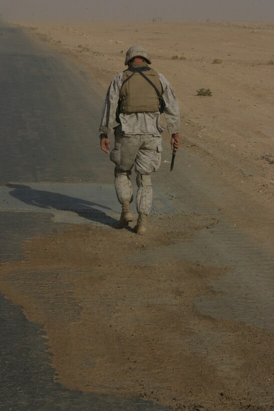 AL ASAD, Iraq (June 23, 2005) - Gunnery Sgt. William S. Barnes, staff noncommissioned officer-in-charge with the Military Police Detachment, Combat Logistics Battalion 2, 2d Force Service Support Group (Forward), walks down Alternate Supply Route Tin looking for possible mines or improvised explosive devices. The Maysville, Miss., native, along with the other Marines from 5th Squad, leave the base a few hours prior to the convoy, searching the route traveled between Al Asad and Al Qaim for anything that may cause a threat to the convoy.