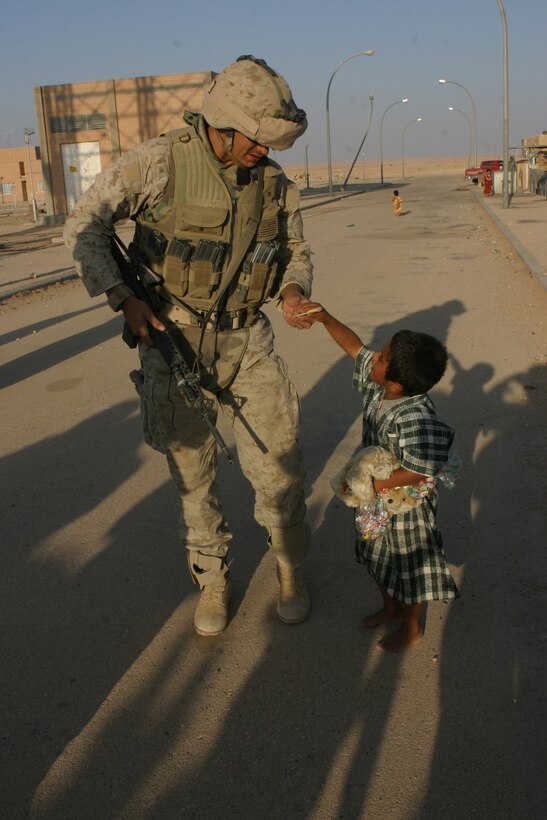 AL ASAD, Iraq (June 23, 2005) - Sergeant Jason A. Cronin, a communication specialist with Combat Logistics Battalion 2, 2d Force Service Support Group (Forward), gives a local Iraqi child a treat at one of the train stations.  The Reston, Va., native, occasionally attaches to 5th Squad, Military Police Detachment here to assist with the Brikwal Patrols. The squad travels Alternate Supply Route Tin looking for possible mines or improvised explosive devices prior to the convoy traveling the road.