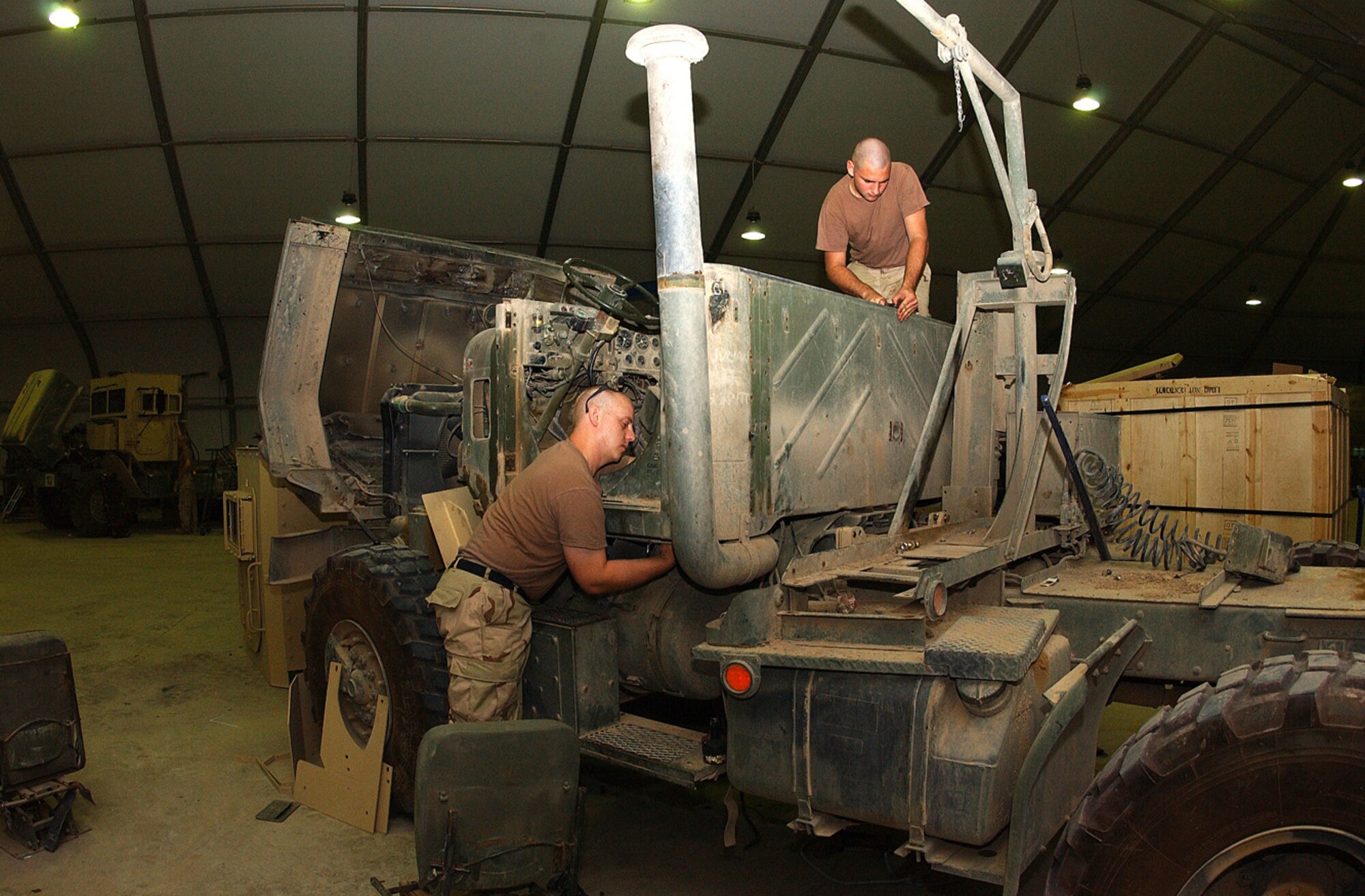 BALAD AIR BASE, Iraq -- Airman 1st Class Joshua Paden (left) installs armor plating to the floor of a vehicle while Airman 1st Class William Hampton prepares to install a rear cab seal here June 23.  The Airmen are vehicle maintainers assigned to the 732nd Expeditionary Mission Support Group's add-on armor shop. (U.S. Air Force photo by Senior Airman Tim Beckham)