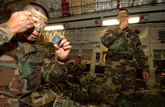 OVER AUSTRALIA -- Army paratroopers apply camouflage to their face before a nighttime airdrop from a C-17 Globemaster III on June 19 over Rockhampton, Australia, as part of the Talisman Saber 2005.  Six C-17s from McChord Air Force Base, Wash., and Charleston AFB, S.C., participated in the airdrop as part of the international military exercise designed to improve combat readiness. (U.S. Air Force photo by Tech. Sgt. Rick Sforza)