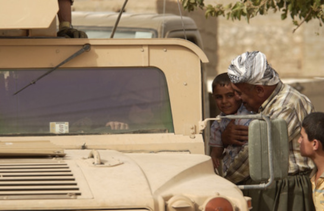 An Iraqi man proudly shows his grandson to a U.S. soldier waiting in his Humvee during a search of houses for weapons and contraband in a Kurdish neighborhood in Tuz, Iraq, on June 19, 2005. Soldiers of the Army's 278th Regimental Combat Team are working with Iraqi soldiers from the 3rd Company, 2nd Squadron, 4th Task Force to conduct the cordon and search mission. 