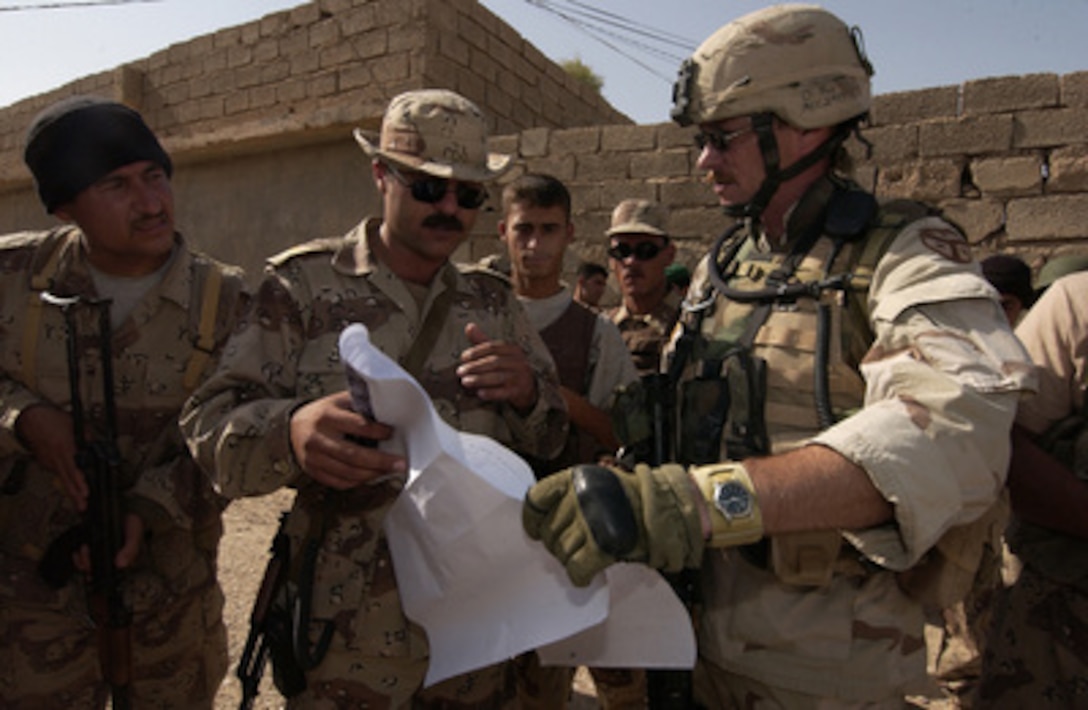 Army Sgt. Mike McClanahan (right) reviews a map with an Iraqi soldier as prepare to search houses for weapons and contraband in a neighborhood in Tuz, Iraq, on June 20, 2005. McClanahan is attached to the Army's 278th Regimental Combat Team and is working with Iraqi soldiers from the 3rd Company, 2nd Squadron, 4th Task Force to conduct the cordon and search mission. 
