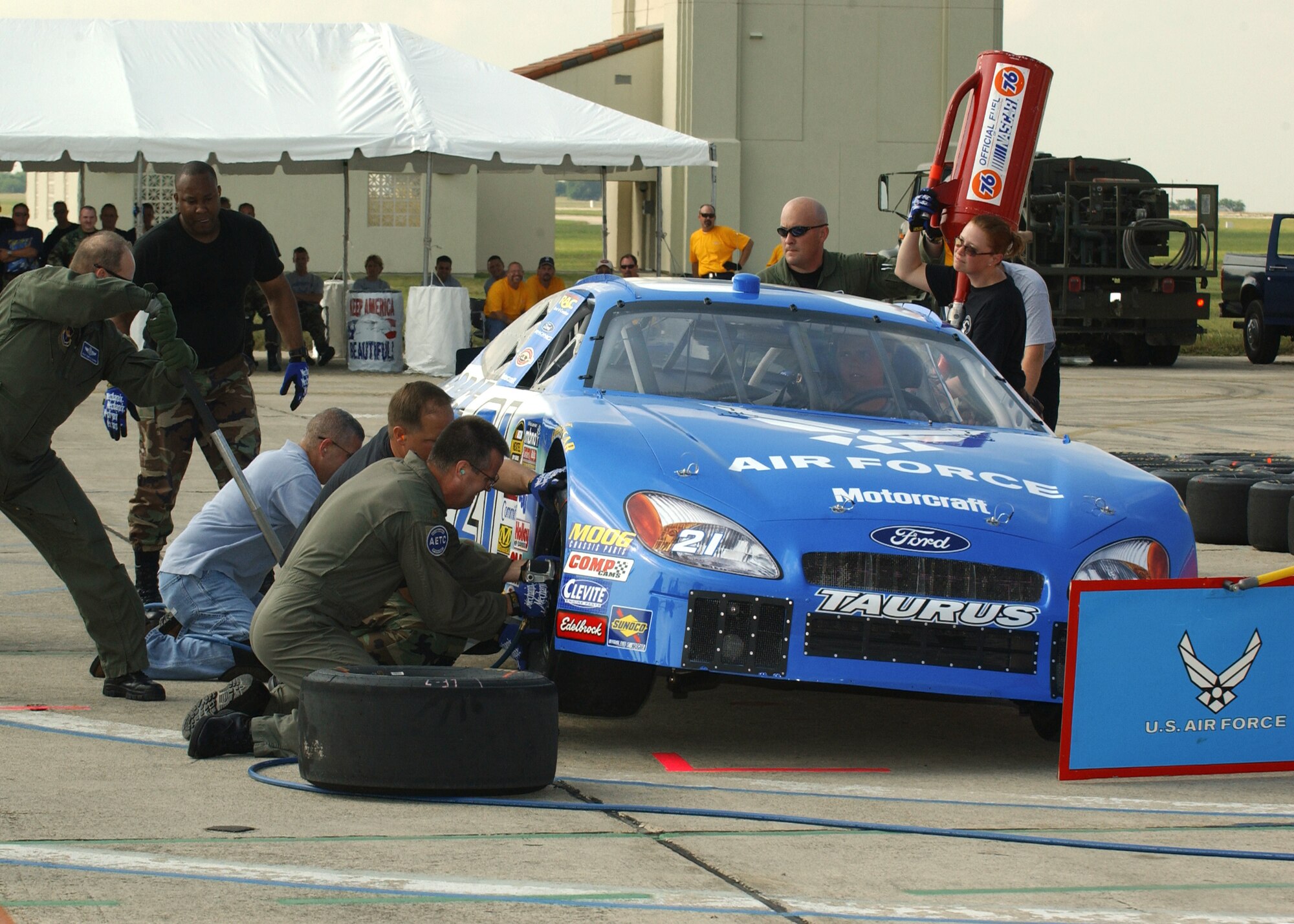 RANDLOPH AIR FORCE BASE, Texas -- Airmen with the Air Education and Training Command's operations directorate and 19th Air Force team  perform a pit-stop routine, including changing two tires and simulating filling the gas tank, on the NASCAR No. 21 Air Force car during a pit-stop competition here June 23.  The AETC team finished in first place at 13.73 seconds.  (U.S. Air Force photo by Larry McTighe)